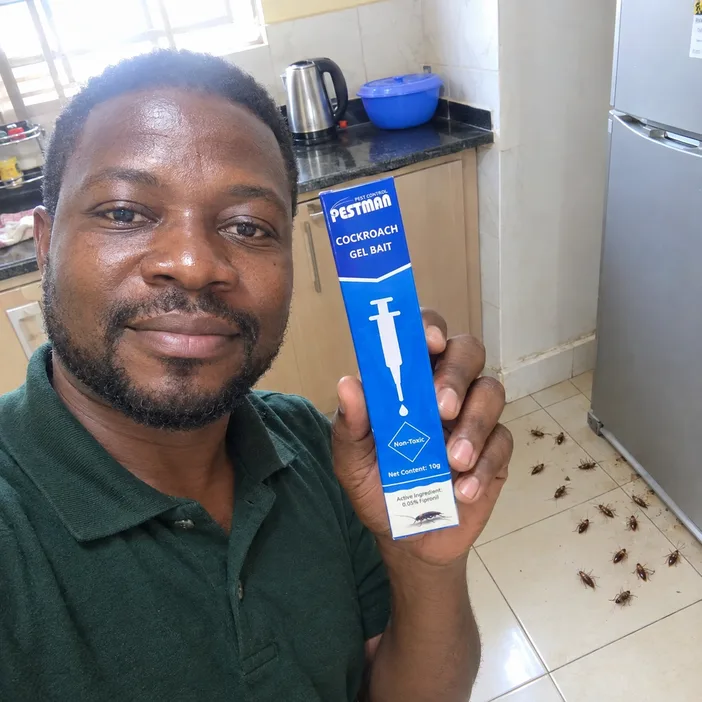 Yaw holding the Pestman pack in his kitchen in Sunyani with dead cockroaches on the floor behind him